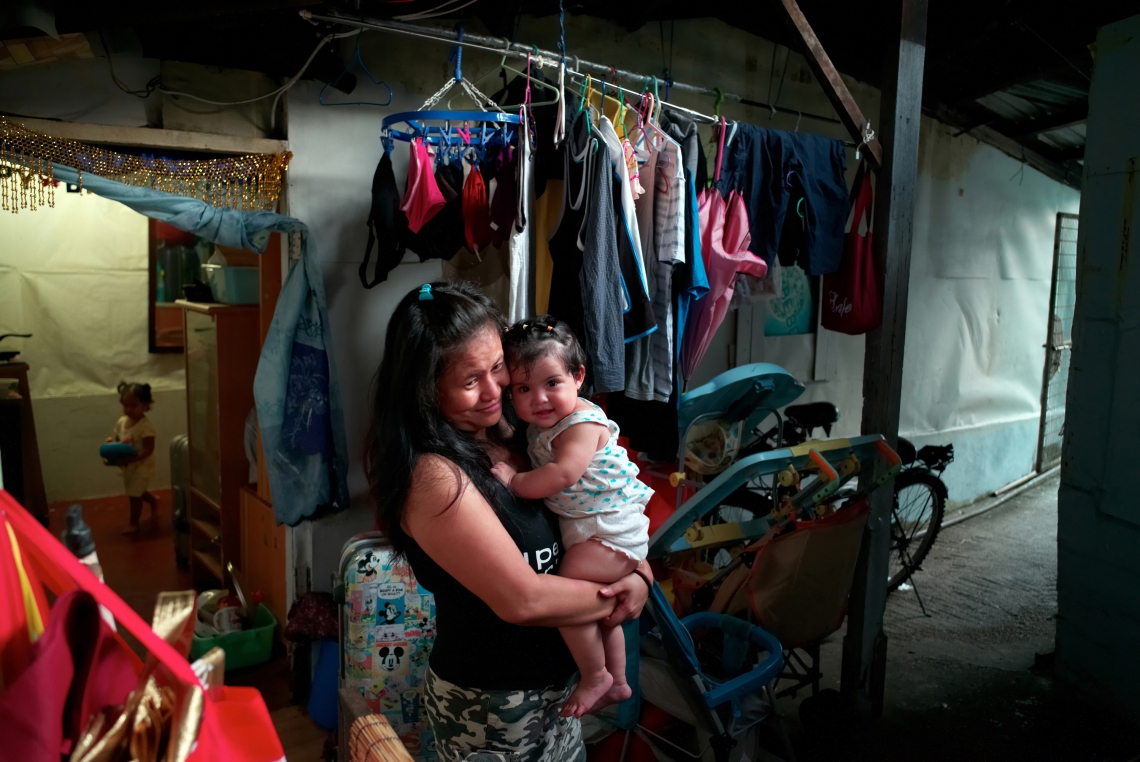 Suneisha 是一名三十歲的印尼人，她在藍地破落的的房子內，抱著鄰居的女兒。來自社會組織的補貼對有兒童的家庭遠遠不足。香港，2015年7月。